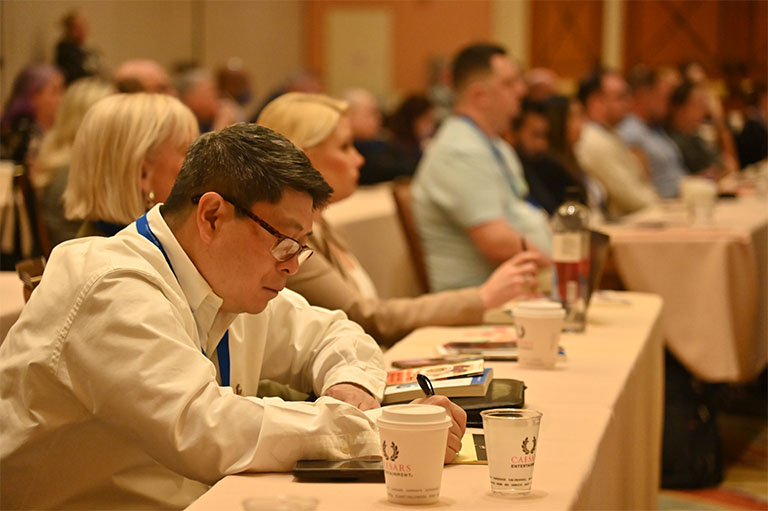 attendees taking notes during conference presentations